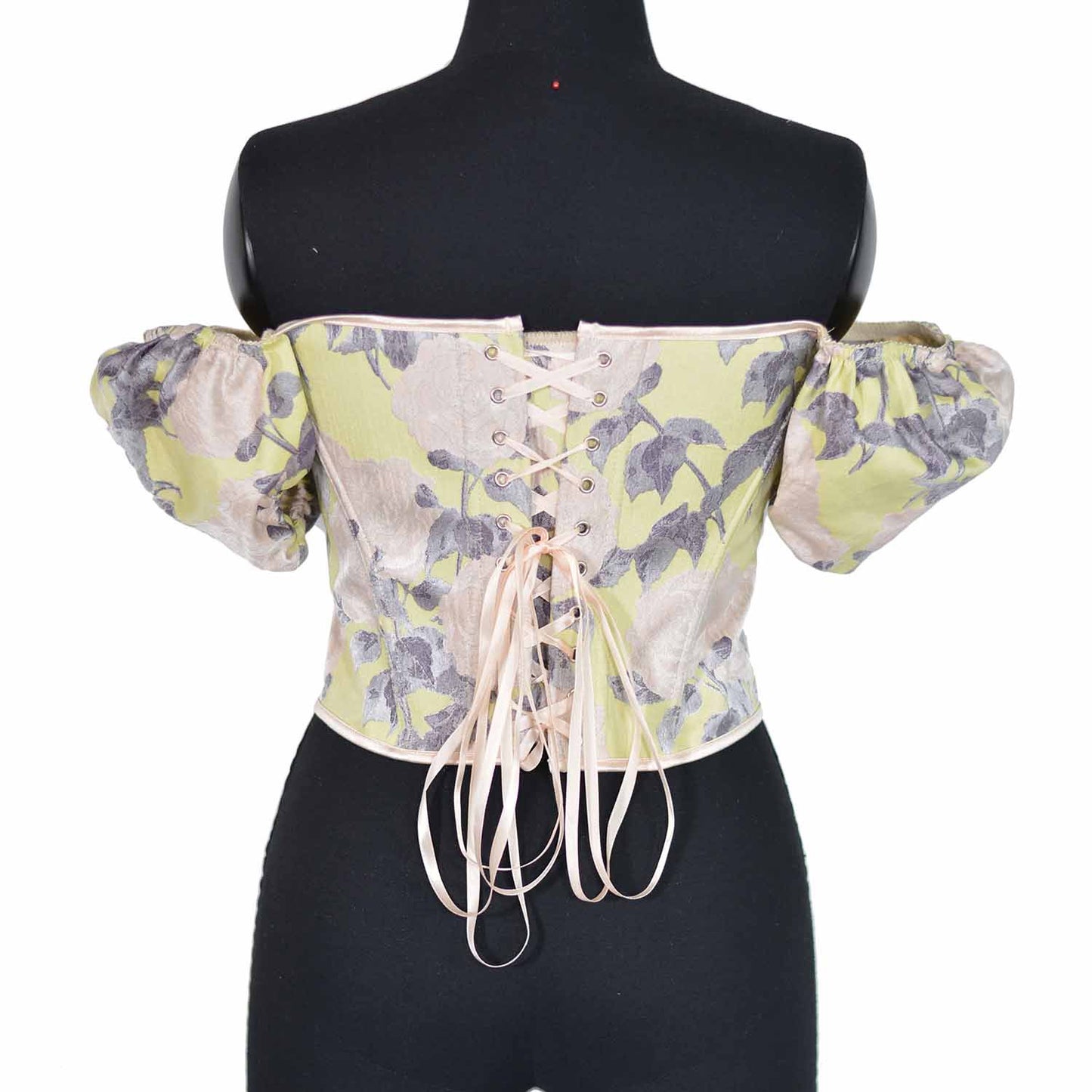 An off-the-shoulder corset top with a pale yellow and gray floral pattern, displayed on a black mannequin torso against a white background.